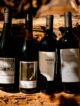 Four bottles of wine perched against a wood log