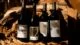 Four bottles of wine perched against a wood log