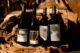Four bottles of wine perched against a wood log